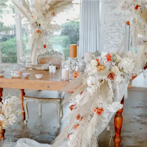 Table setting with pampas grass and peach-and-rust dried florals in bright daylight