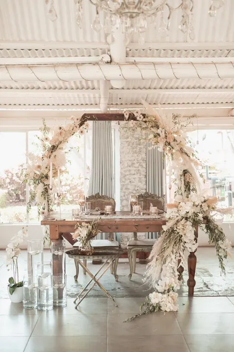 Sweetheart table beneath a dried protea and pampas floral arch