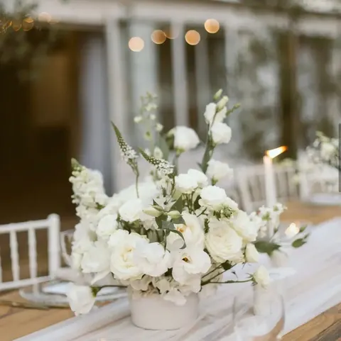 Table centerpiece with soft string-light bokeh behind white blooms