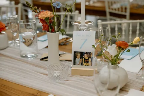 Table number styled with orange ranunculus and pale blue delphinium