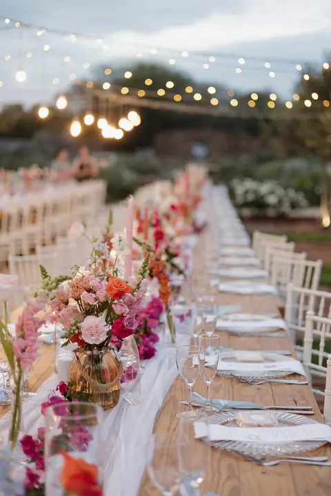Vivid pink and coral floral garland runner along a reception table
