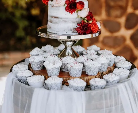 Naked wedding cake and cupcakes topped with red dahlias, blush roses and ranunculus