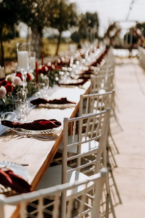 White chiavari chairs lined along a wooden reception table
