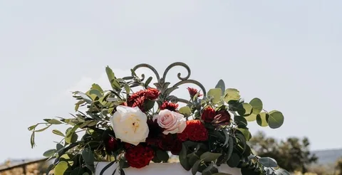 Red, white and blush floral swag detail, iron scrollwork against open sky