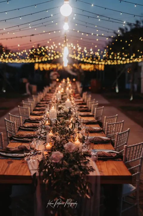 Dusk reception tablescape with blush roses under hanging string lights