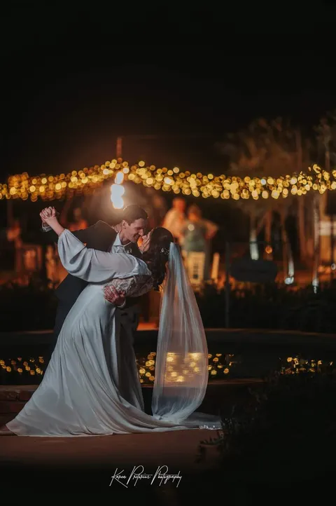 Bride and groom sharing a first dance under string lights at night