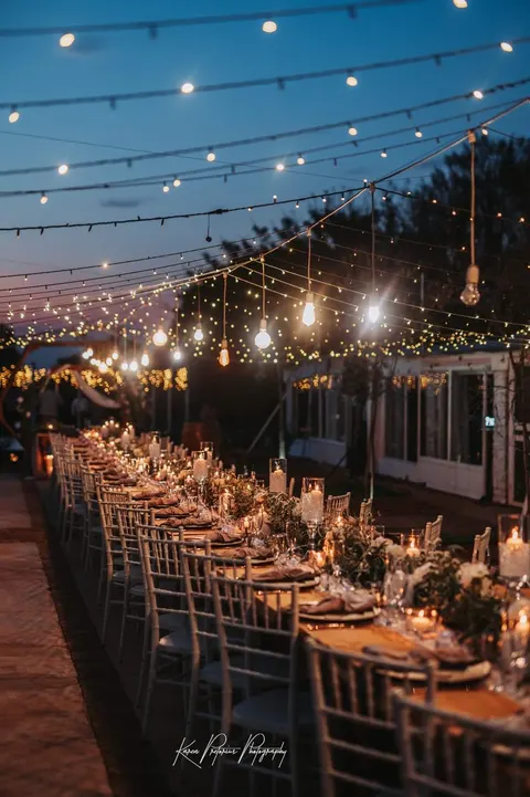 Evening reception table row under a canopy of string lights