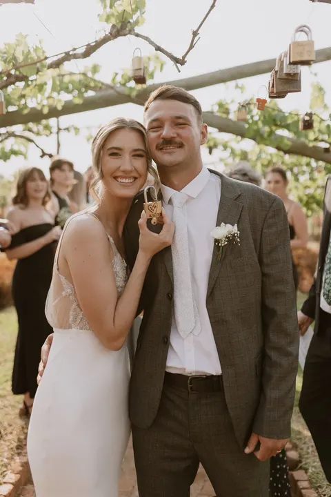 Couple with a padlock keepsake beneath vines hung with love locks